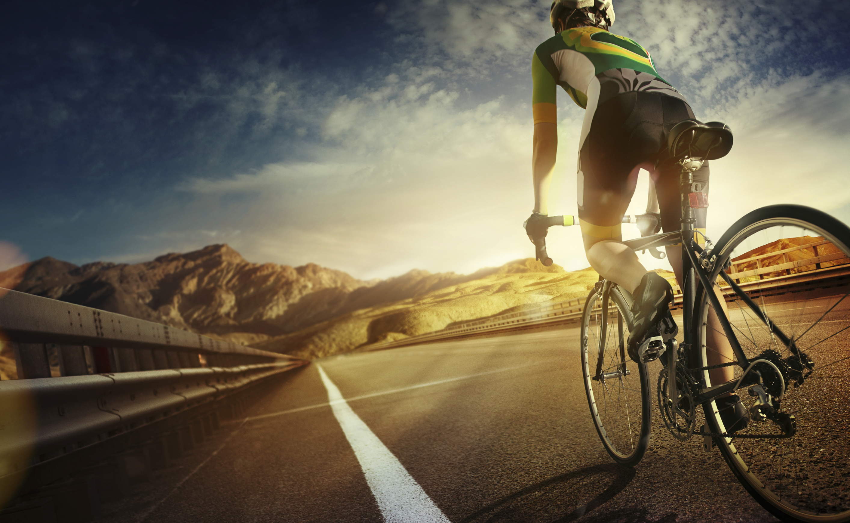 Cyclist riding a bike to the sunset on the highway